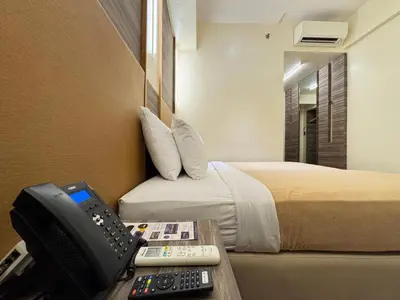 a hotel room with a phone and a bed at Kabayan Hotel Pasay in Manila