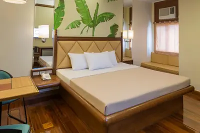 a bedroom with a bed and a desk with a telephone at Kabayan Hotel Pasay in Manila