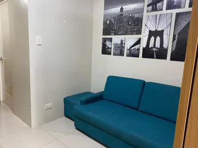 a blue couch in a room with pictures on the wall at Shell Residences C21 Shortwalk Sm Mall Of Asia Airport in Manila