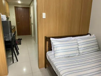 a bed with striped pillows in a room at Shell Residences C21 Shortwalk Sm Mall Of Asia Airport in Manila