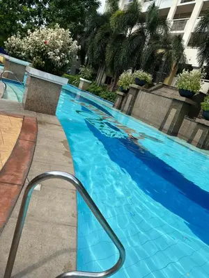 a blue swimming pool with a handrail in a building at B-G Sorento Oasis 2BR in Manila