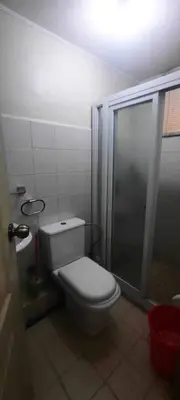 a small bathroom with a toilet and a shower at B-G Sorento Oasis 2BR in Manila