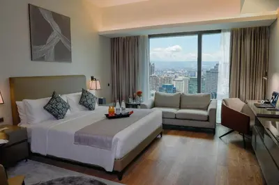 a bedroom with a large bed and a living room at Oakwood Makati Avenue in Manila
