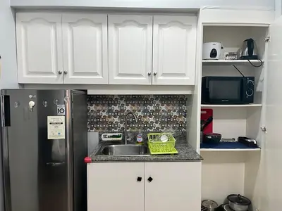 a kitchen with white cabinets and a sink and a refrigerator at Ultimate getaway in Alabang at Anuva Residences in Manila