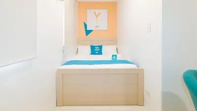 a small bedroom with a bed with a wooden headboard at Sans Hotel at One JD Place Makati by RedDoorz in Manila