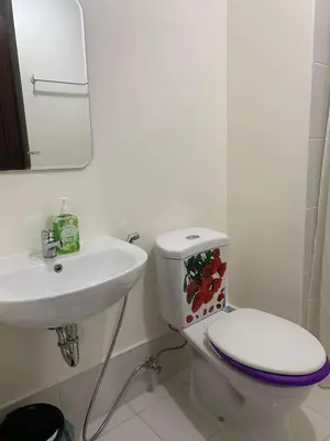 a white bathroom with a toilet and a sink at Relaxing Haven at Covent Garden in Manila