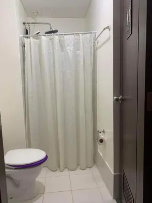 a bathroom with a shower curtain and a toilet at Relaxing Haven at Covent Garden in Manila