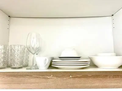 a shelf with plates and bowls and a wine glass at MALL OF ASIA 1156 Affordable Staycation DYNASTEL SHORE in Manila