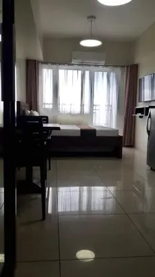 a bedroom with a bed and a table and a chair at Studio unit at The Breeze Residence in Manila