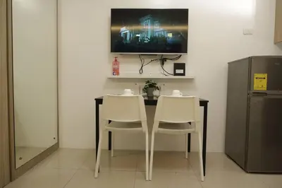 a dining room table with two white chairs and a television at MOA ARENA 1151 DYNASTEL SHORE Staycation in Manila