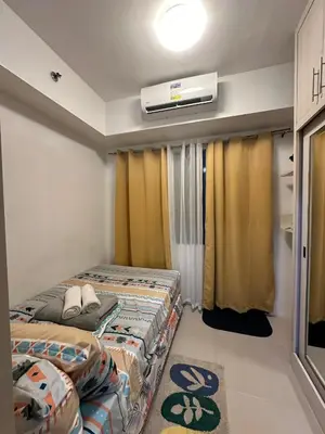 a small room with two beds and a air conditioner at Sea Residences MOA Pasay City - Ruffa's Condotel in Manila