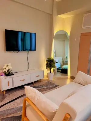 a living room with a couch and a tv on a wall at Condotel Across Naia T3 at ONE PALM TREE VILLA CLUSTER B in Manila