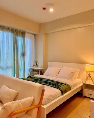 a bedroom with a large bed and a window at Condotel Across Naia T3 at ONE PALM TREE VILLA CLUSTER B in Manila