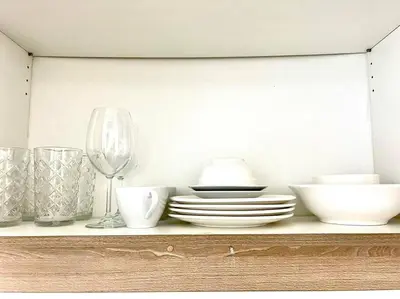 a shelf with plates and bowls and a wine glass at CONDOTEL STAYCATION 793 Pasay DYNASTEL in Manila