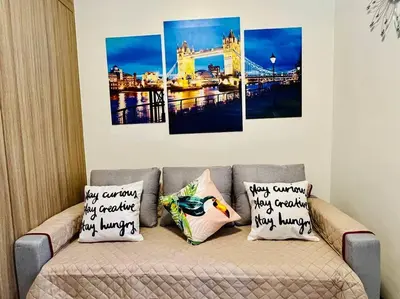 a living room with a couch with four paintings on it at MOA PASAY 1478 Dynastel Shore Staycation in Manila