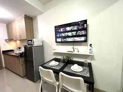 a small kitchen with a table and chairs and a refrigerator at Shore Residences 1576 Dynastel Staycation in Manila