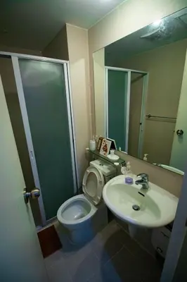 a bathroom with a toilet and a sink and a mirror at Cozy Chic Condotel Azure Urban Resort Residences in Manila