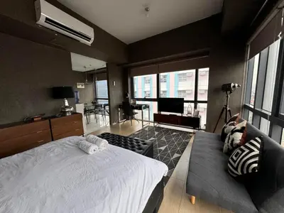 a bedroom with a large bed and a living room at Modern Studio at NAIA Terminal 3 in Manila