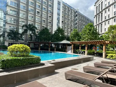 a swimming pool with lounge chairs and a large building at Modern Studio at NAIA Terminal 3 in Manila