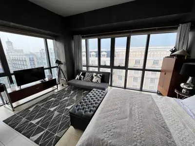 a bedroom with a bed and a couch and large windows at Modern Studio at NAIA Terminal 3 in Manila