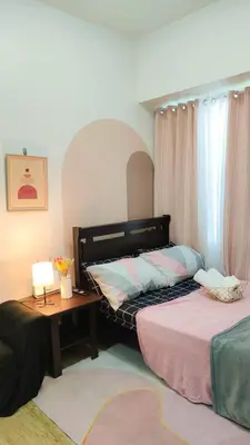 a bedroom with a bed and a table with a lamp at anuva residences room 1 in Manila