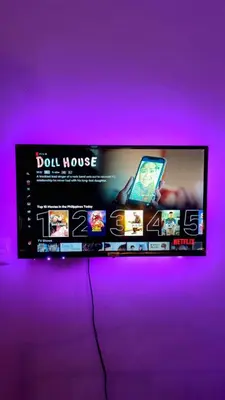 a tv with a purple wall with a poster of a doll house at anuva residences room 1 in Manila