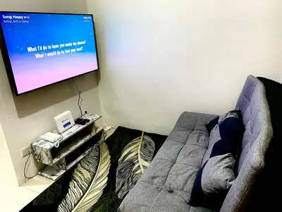 a living room with a couch and a flat screen tv at aesthetic suite in edsa smdc fame VERY FAST WIFI in Manila