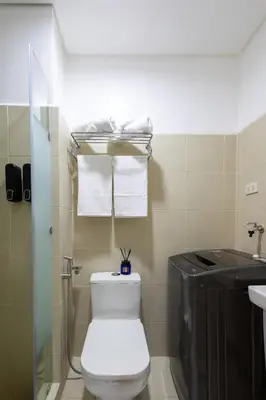 a bathroom with a toilet and a sink with towels at Lush Residences Makati in Manila
