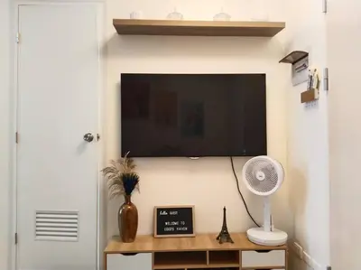 a flat screen tv on a wall with a fan at 2BR Condo by Coco's Haven in Manila