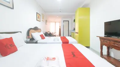 a hotel room with two beds and a flat screen tv at RedDoorz at TJMG by Bel Air Polaris Makati in Manila