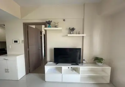 a living room with a television on a white entertainment center at 150 Newport Boulevard, near Terminal3 Airport in Manila