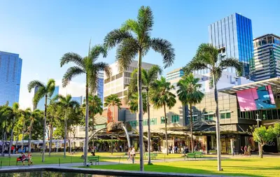 a park with palm trees in front of a building at HUGE 2BR BGC Suite 70sqm, Perfect for 6, Balcony, Pool & Uptown Mall Connector, Ste 25 in Manila
