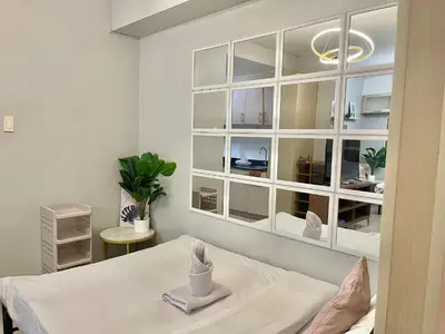 a white room with a bed and a mirror at PinkDoorZ MOA Staycation at SEA Residences in Manila