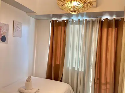 a bedroom with a bed with curtains and a chandelier at PinkDoorZ MOA Staycation at SEA Residences in Manila