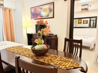 a dining room table with a bowl of flowers on it at PinkDoorZ MOA Staycation at SEA Residences in Manila