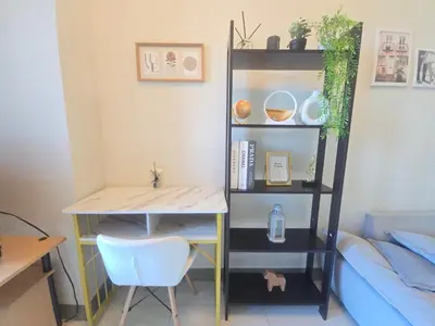 a desk and a shelf with a table and a chair at Cosy BGC Uptown Parksuites with Nice Balcony City View and Ultra Fast Internet 300mbps in Manila