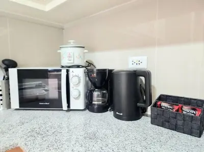a kitchen counter with a microwave and a coffee maker at Cosy BGC Uptown Parksuites with Nice Balcony City View and Ultra Fast Internet 300mbps in Manila