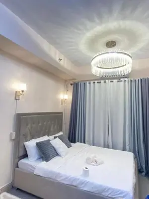 a bedroom with a large white bed with a chandelier at Grace Residences Elevate Escapes - near BGC airport in Manila