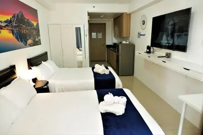 a hotel room with two beds and a television at Mall of Asia Shore Dynastel Staycation in Manila
