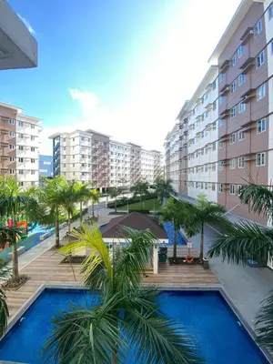 a resort with a pool and palm trees and buildings at Davids Suite at Hope Residences Trece Martires Cavite in Trece Martires