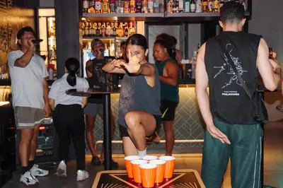 a woman standing in a bar with a tray of beers at Mad Monkey Manila in Manila