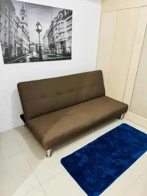 a bench in a room with a painting and a blue rug at Ever Stays at Light Residences 1BR in Manila