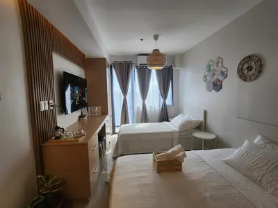 a bedroom with two beds and a desk and a window at Goshen E320 in Manila
