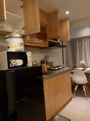 a kitchen with wooden cabinets and a microwave at A2J Luxury 2BR BGC Suite Near High Street, Malls in Manila
