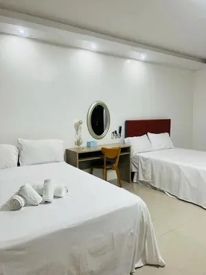 a hotel room with two beds and a desk at Shiri Hotel in Silang