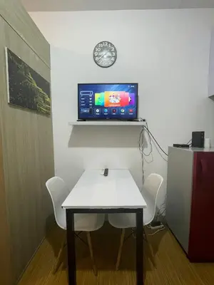 a room with a table and a tv on a wall at Grace Residences Pool View Free Wi-Fi near BGC and McKinley 2050 in Manila