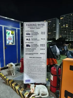 two dogs laying next to a parking rates sign at Shore 2 Residences T1, MoA WTC SMX Arena 1br 4pax in Manila