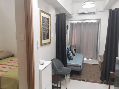 a bedroom with a bed and a chair and a window at Shore 3 in Manila