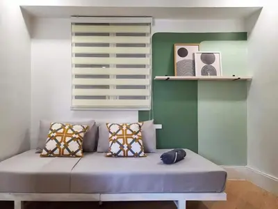 a couch in a room with a window and shelves at BGC - Two Bedroom Condo with Game Room high speed WiFi in Manila