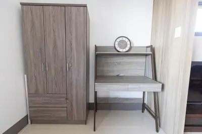 a desk with a clock next to a wooden cabinet at Bohemian 1-BR Condo in Mandaluyong in Manila